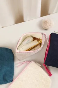 Corduroy makeup bag detail showing soft texture zipper pull and tidy cosmetic storage pouch.