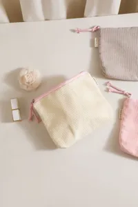 Close-up detail of corduroy cosmetic bag with zipper and cute rope pull, perfect travel storage.