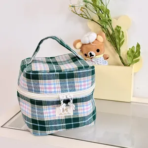 Detailansicht einer grünen karierten Kosmetiktasche mit Tragegriff und Reißverschluss.