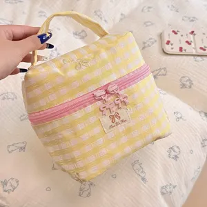 Yellow checkered cosmetic bag with cute bows and pink zipper for daily travel storage.