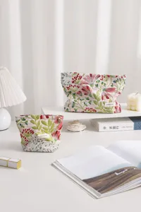 Detailed shot of floral embroidered cosmetic bag showing fine fabric texture and stylish zipper pull.