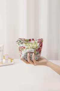 Floral embroidered fabric cosmetic bag detail view, portable zipper pouch with woven label.