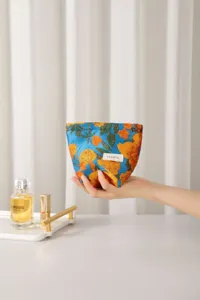 Vista dettagliata della pochette cosmetica in tessuto jacquard floreale vintage, blu e giallo.