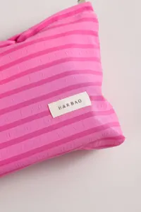 Primer plano detallado del neceser de maquillaje a rayas rosas con etiqueta textil.