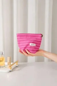 Primer plano detallado del neceser de cosméticos a rayas rosas con cierre floral, portatil.