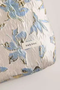 Detailed view of the elegant metallic jacquard cosmetic bag fabric featuring charming blue flowers.