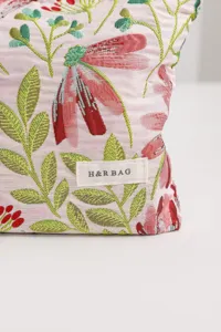Floral fabric cosmetic bag detail view featuring woven cosmos flower pattern and label.