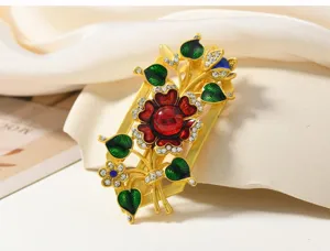 Gros plan pince a cheveux florale en email dore avec pierre rouge et strass brillants.