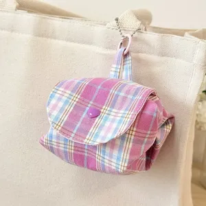 Close-up detail of the cute pink and blue plaid storage pouch with heart button and chain.