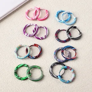 Detailed view of colorful gradient stainless steel hoop earrings, enameled surface close-up.