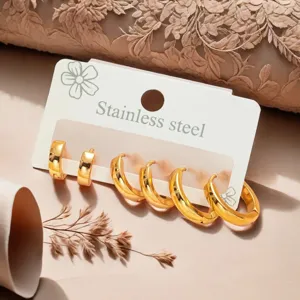 Detailed close-up view of minimalist gold stainless steel hoop earrings set on white card.