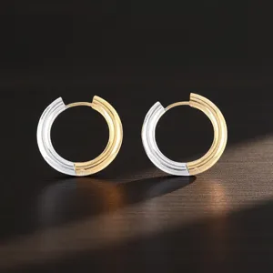 Close-up detail shot of stylish two-tone stainless steel hoop earrings with gold and silver.