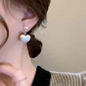 Detailed close-up shot of the stunning S925 silver brushed pearl heart earrings on ear.