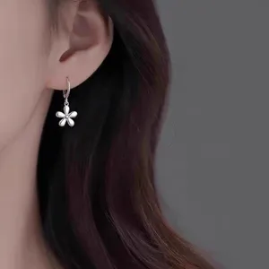 Close-up detail of silver floral drop earrings worn by model, elegant simple hoop style.