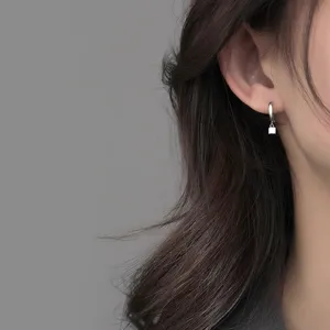 Gros plan détaillé de boucles d'oreilles créoles carrées en argent, style minimaliste chic.