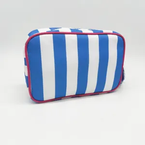Blue and white striped cosmetic bag detail view showing neat pink piping and blue tassel zipper.