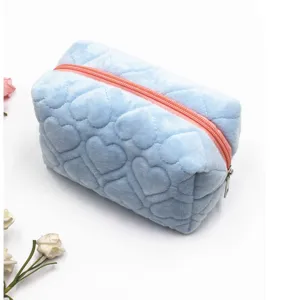 Detalle en primer plano del neceser de felpa azul claro acolchado con un bonito diseño de corazones.
