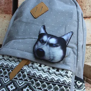 Close-up detail of grey polka dot canvas backpack featuring 3D husky dog badge and geometric pattern.