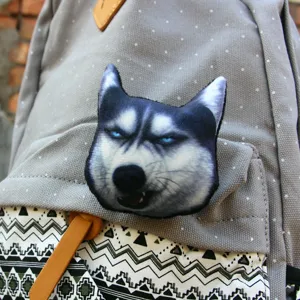 Detail shot of creative 3D husky dog head plush brooch badge on grey canvas backpack.