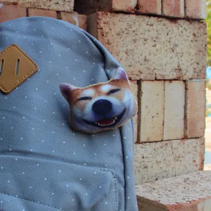 3D cute Shiba Inu dog head plush brooch badge attached on grey polka dot backpack detail view.