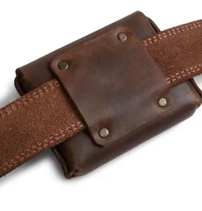 Detailopname van bruine lederen heuptas met metalen klinknagels en stevige riemluse.