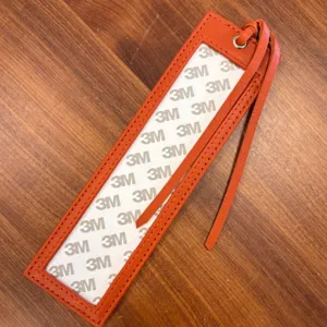 Orange PU leather cross stitch bookmark sleeve featuring transparent window and strap.