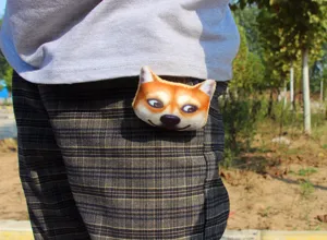 Detail shot of a funny 3d dog head plush brooch worn on plaid pants pocket, soft badge accessory.