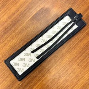Detail shot of PU leather cross-stitch bookmark sleeve with adhesive backing and hanging cord.
