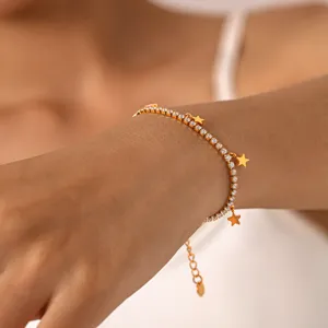 Primo piano di un bracciale tennis in acciaio dorato con zirconi brillanti e ciondoli a stella.