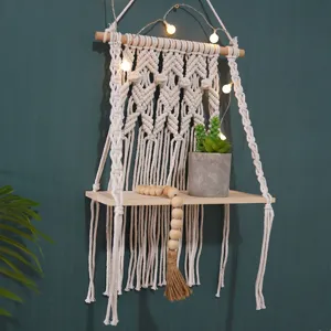 Bohemian woven macrame wall hanging shelf with wooden board and fairy lights for home decor.