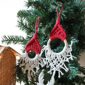 Close up of handmade macrame Christmas hat ornament hanging on tree branch, festive decor detail.