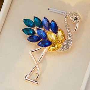 Broche flamant rose en cristal exquise avec des strass étincelants et des plumes bleues vives.