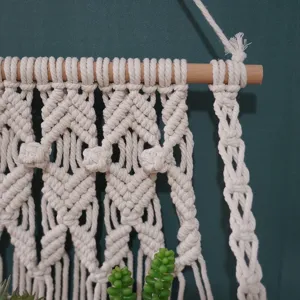 Macrame wall hanging detail shot showing intricate boho braided cotton cord knots and wooden stick.