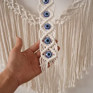 Tenture murale en macramé bohème faite à la main avec perles de mauvais œil et pompons.