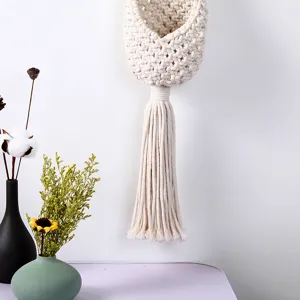 Detailed view of handmade beige macrame wall hanging basket, woven cotton pocket with tassel.