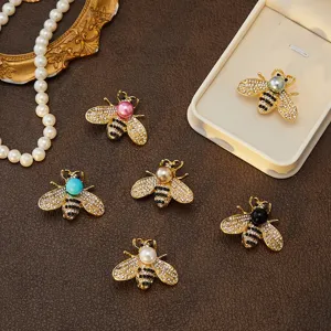 Gros plan de broches abeilles étincelantes en strass et perles de plusieurs couleurs élégantes.