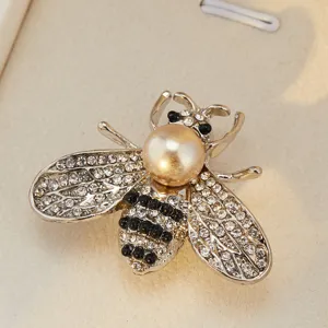 Gros plan détaillé d'une charmante broche abeille en cristal avec perle et strass scintillants.