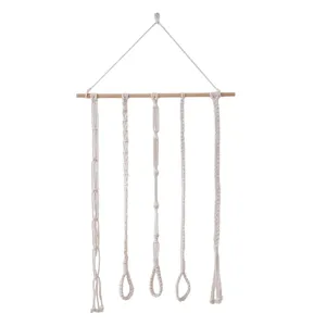 Macrame hair bow holder detail showing cotton rope strands and wooden dowel for wall decor.