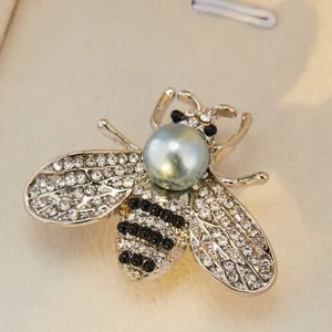 Gros plan détaillé d'une charmante broche abeille en cristal avec perle et strass.