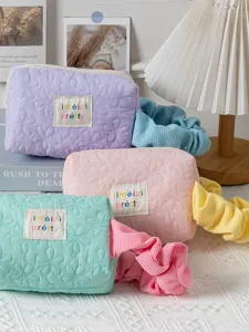 Cute candy-colored quilted cosmetic bag with floral embroidery and portable scrunchie design main view.