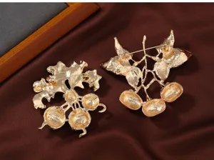 Vista detallada del broche dorado en forma de caqui sobre tela marrón, accesorio de joyería.