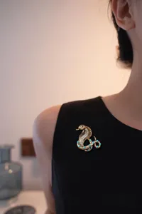Vintage snake brooch with turquoise and rhinestones, elegant retro apparel accessory pin for women.