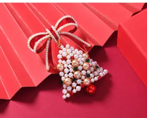 Detail view of Christmas brooch featuring pearl bell, red bow, and festive rhinestone accents.