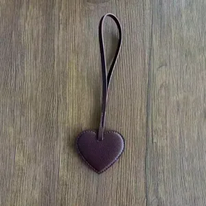 Primer plano detallado del colgante de bolso con corazón de cuero PU morado oscuro y textura.