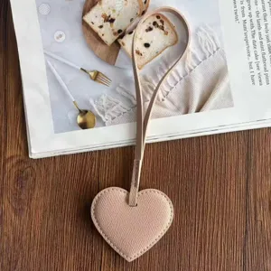 Primer plano del colgante de bolso en forma de corazón de cuero PU rosa sobre madera.
