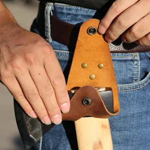 Close-up detail of genuine leather axe protective sheath with snap button worn on waist belt.