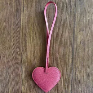 Primer plano detallado del colgante de bolso de cuero PU rosa en forma de corazón en madera.