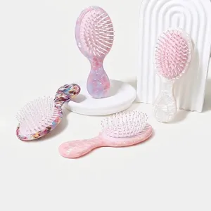 Dettaglio di mini spazzole per capelli a cuscino d'aria con trame colorate in marmo e conchiglia.
