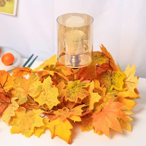 Close-up of artificial autumn maple leaf garland around a glass candle holder