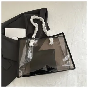 Detailansicht einer rauchschwarzen transparenten PVC-Tragetasche mit weißen Seilgriffen.
